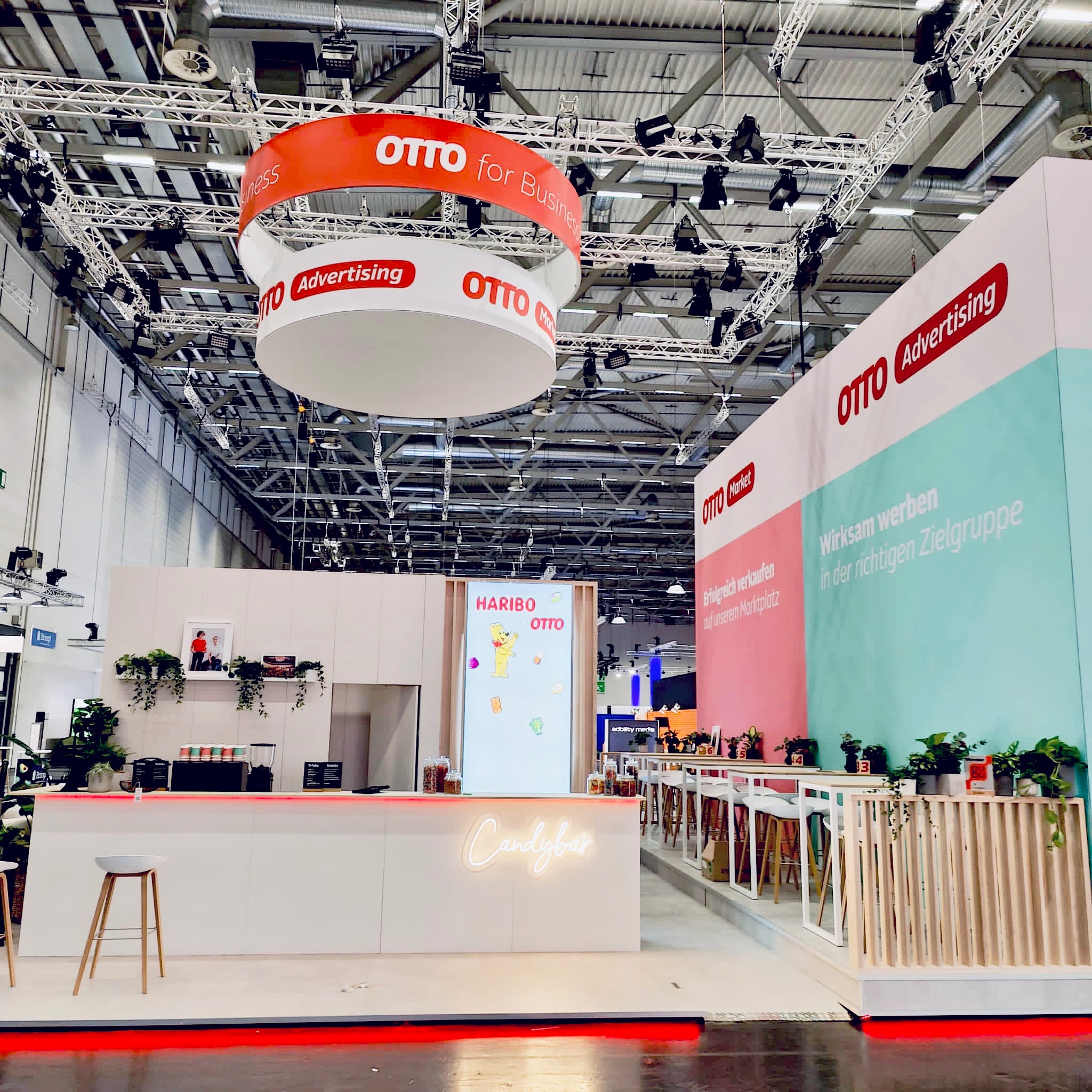 Von urban!scope gebauter OTTO Messestand mit runder Deckenkonstruktion, Empfangstheke und offenen Gesprächsbereichen
